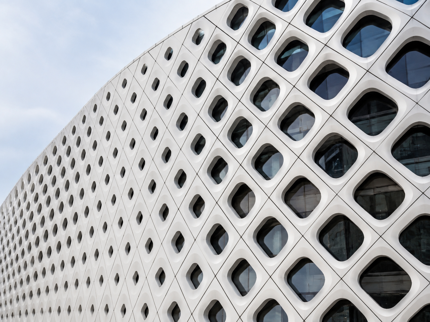 White parametric facade with a gradient of rounded window openings